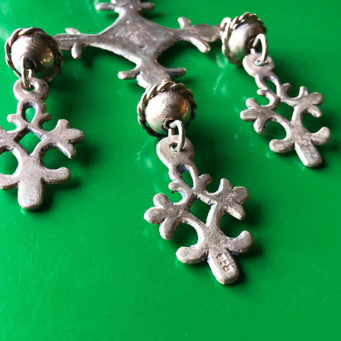 Closeup shot of the backside of the Yalalag pendant on a green wood surface, showing the 925 stamp in the forefront of the image, indicating the piece is sterling silver.
